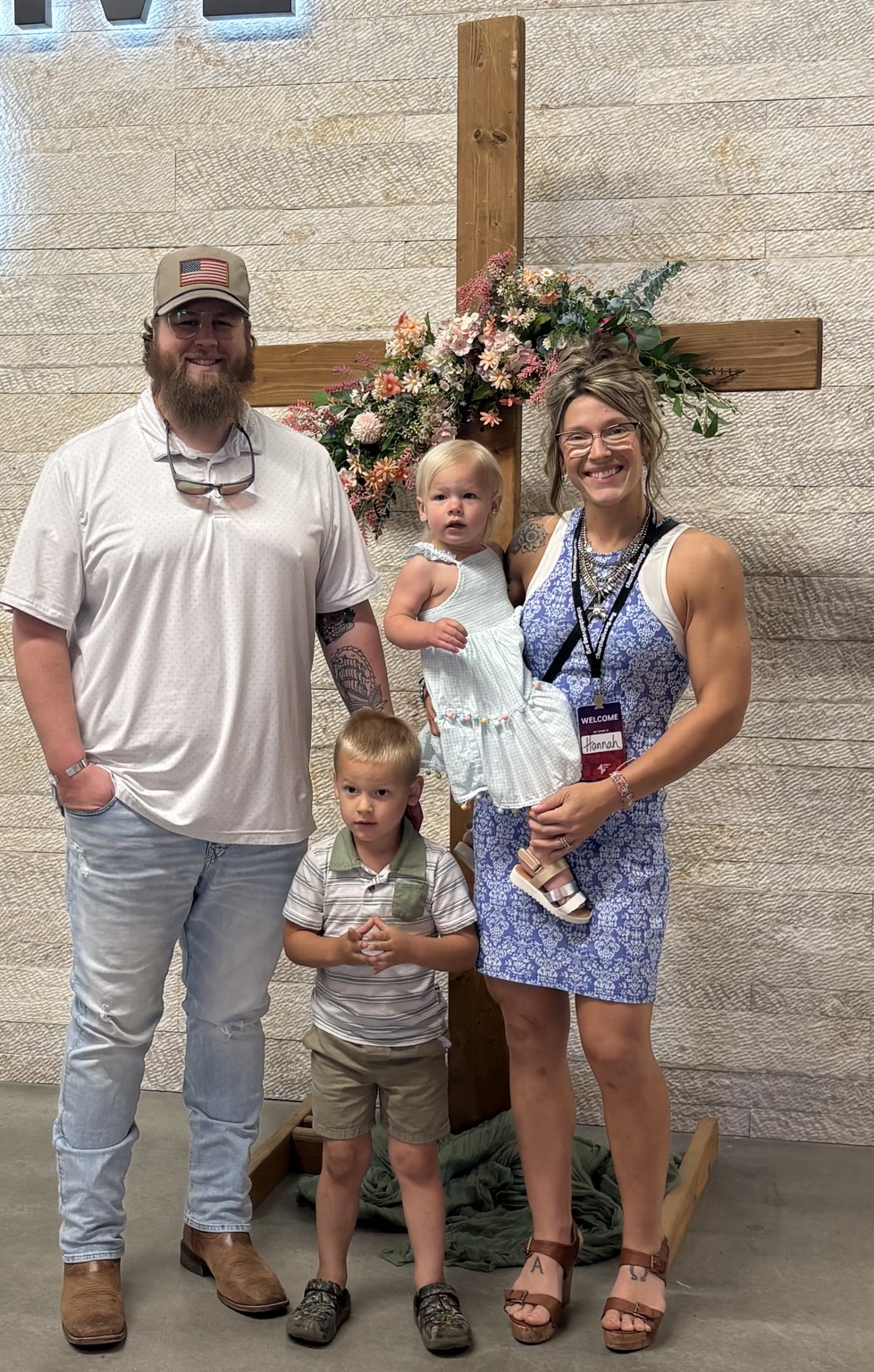 Collin with his wife and children in front of a wooden cross