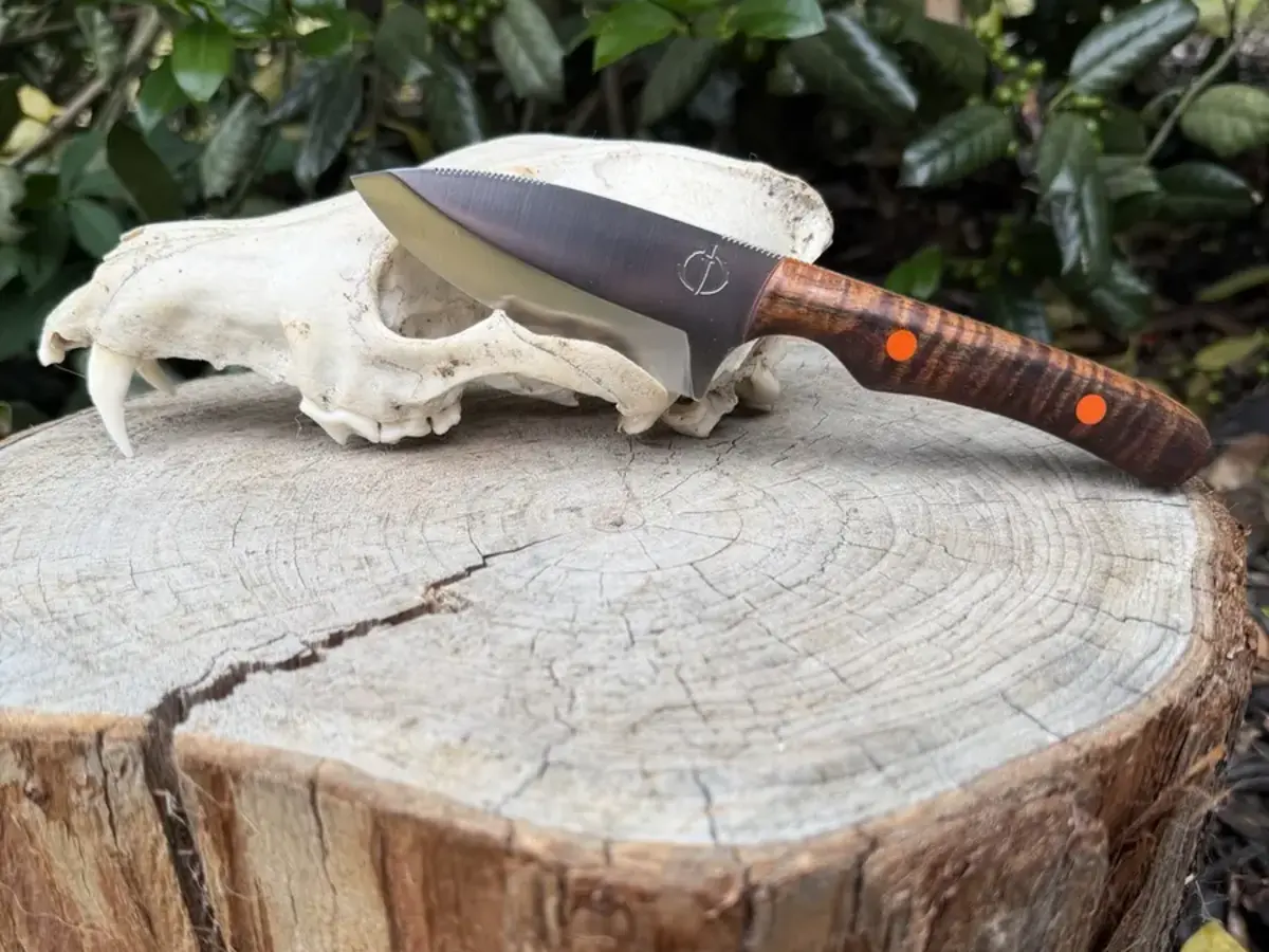 The Exodus handmade knife with a figured wood handle and orange pins
