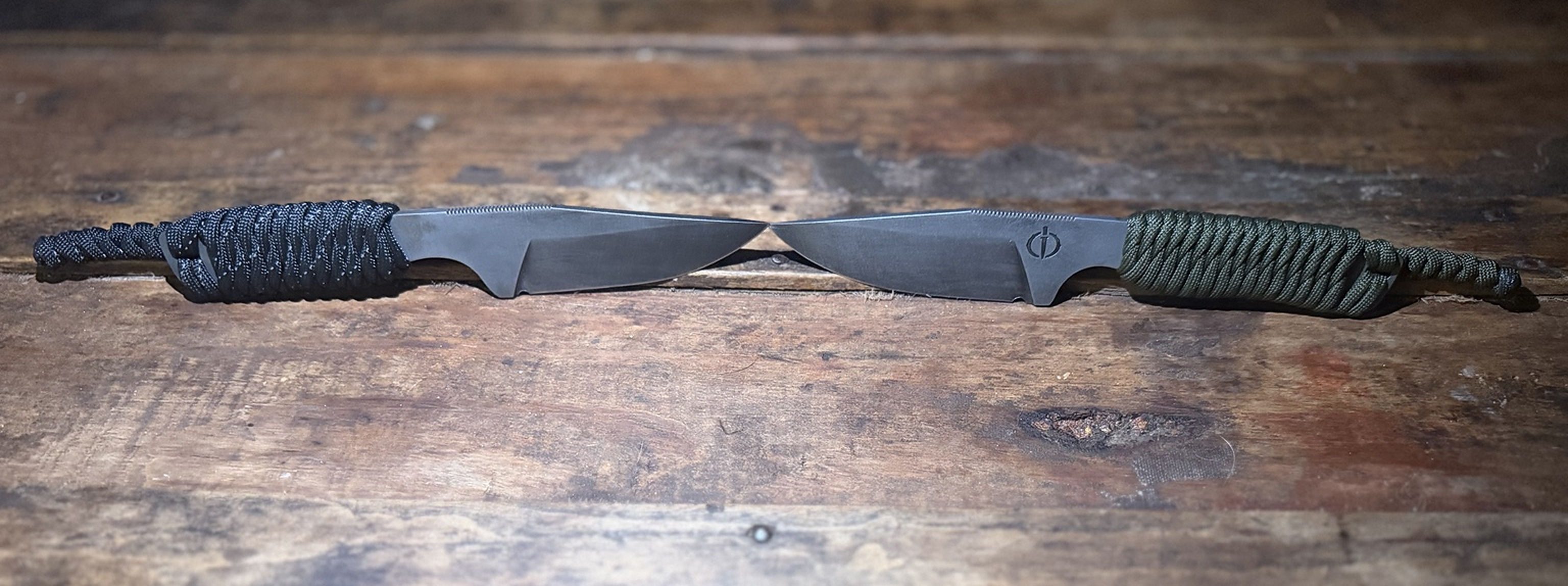 Two handmade Iron Oak fixed-blade knives with black and green paracord-wrapped handles